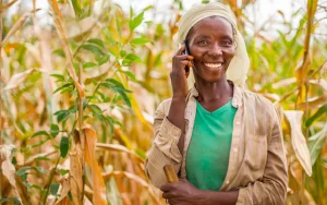 Rural farmer smiling while using a mobile phone in the field, symbolizing digital inclusion through offline-first technology