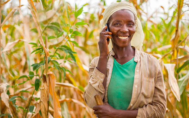 Rural farmer smiling while using a mobile phone in the field, symbolizing digital inclusion through offline-first technology